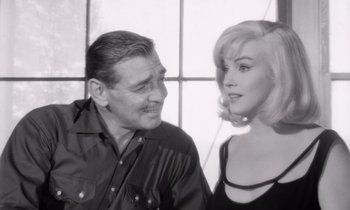 Movie still from “The Misfits” (1961), directed by John Huston – An older man and a younger woman are posing for a picture; Close Up shot, Over the shoulder angle