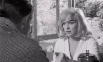 Movie still from “The Misfits” (1961), directed by John Huston – A black - and - white photo of a woman holding a flower; Close Up shot, Over the shoulder angle