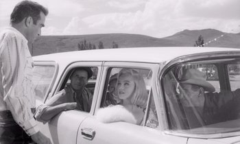 Movie still from “The Misfits” (1961), directed by John Huston – A man and a woman sitting in the back of a car; Medium shot, Over the shoulder angle