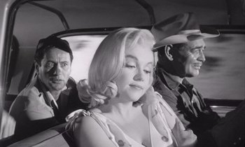 Movie still from “The Misfits” (1961), directed by John Huston – A woman sitting in the back of a car with two other men; Medium shot, Low angle