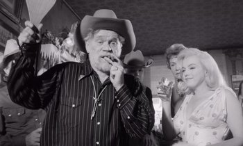 Movie still from “The Misfits” (1961), directed by John Huston – An older man wearing a cowboy hat smoking a cigarette; Medium shot, Low angle