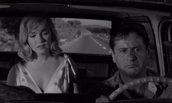 Movie still from “The Misfits” (1961), directed by John Huston – A man and a woman in the back seat of a car; Medium shot, Over the shoulder angle