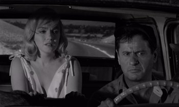 Movie still from “The Misfits” (1961), directed by John Huston – A man and a woman in the back seat of a car; Close Up shot, Over the shoulder angle
