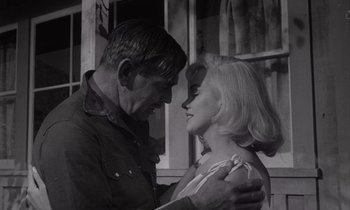 Movie still from “The Misfits” (1961), directed by John Huston – An older man and a younger woman embracing each other in front of a window; Close Up shot, Low angle