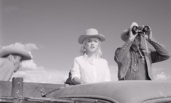 Movie still from “The Misfits” (1961), directed by John Huston – A man and a woman are standing on the hood of an old car; Medium shot, Low angle