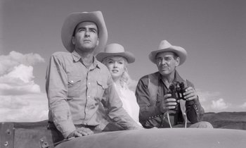 Movie still from “The Misfits” (1961), directed by John Huston – A group of people standing next to each other on a field; Medium shot, Low angle