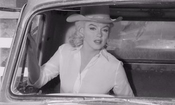 Movie still from “The Misfits” (1961), directed by John Huston – A woman wearing a cowboy hat sitting in the back seat of a car; Medium shot, Low angle