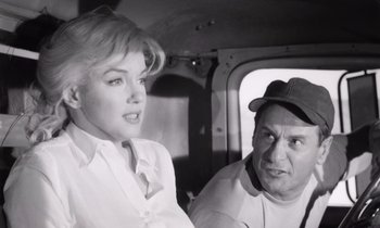 Movie still from “The Misfits” (1961), directed by John Huston – A man and a woman are sitting in a helicopter; Medium shot, Low angle