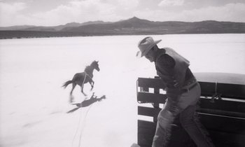 Movie still from “The Misfits” (1961), directed by John Huston – A man riding a horse in the middle of the snow; Wide shot, Low angle