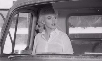 Movie still from “The Misfits” (1961), directed by John Huston – A black and white photo of a woman in a car; Medium shot, Low angle