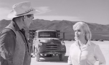 Movie still from “The Misfits” (1961), directed by John Huston – A man and a woman standing in front of an old truck; Medium shot, Over the shoulder angle