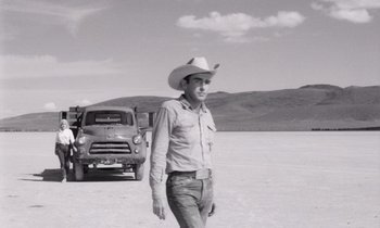 Movie still from “The Misfits” (1961), directed by John Huston – A man wearing a cowboy hat standing in front of a truck; Medium shot, Low angle