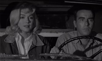 Movie still from “The Misfits” (1961), directed by John Huston – A man and a woman sitting in the drivers seat of a car; Medium shot, Over the shoulder angle