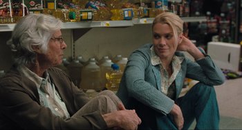 Movie still from “The Mist” (2007), directed by Frank Darabont – A woman and a man sitting next to each other in a store; Medium shot, Over the shoulder angle