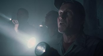 Movie still from “The Mist” (2007), directed by Frank Darabont – A man holding a flashlight in a dark room; Close Up shot, Low angle