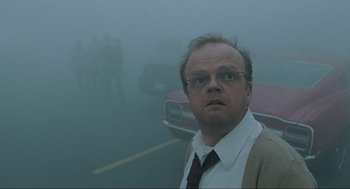 Movie still from “The Mist” (2007), directed by Frank Darabont – A man in a suit and tie standing in the middle of a road; Close Up shot, Over the shoulder angle