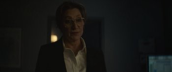 Movie still from “The Mother” (2023), directed by Niki Caro – An older woman wearing glasses and a suit; Close Up shot, Over the shoulder angle