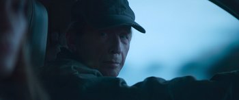 Movie still from “The Mother” (2023), directed by Niki Caro – A person wearing a hat; Close Up shot, Low angle