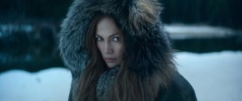Movie still from “The Mother” (2023), directed by Niki Caro – A woman with long hair and a fur coat on; Close Up shot, High angle