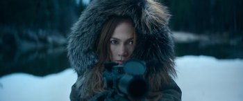 Movie still from “The Mother” (2023), directed by Niki Caro – A woman in a fur coat is holding a camera; Close Up shot, Over the shoulder angle