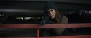 Movie still from “The Mother” (2023), directed by Niki Caro – A woman is holding a gun and aiming at something; Close Up shot, Over the shoulder angle