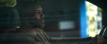 Movie still from “The Mother” (2023), directed by Niki Caro – A person looking out a window; Close Up shot, Over the shoulder angle