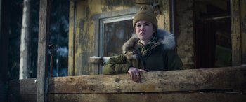 Movie still from “The Mother” (2023), directed by Niki Caro – A young man wearing a winter coat and a hat; Close Up shot, Low angle