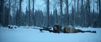 Movie still from “The Mother” (2023), directed by Niki Caro – Two women laying in the snow with a rifle; Wide shot, Low angle