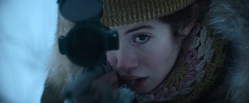 Movie still from “The Mother” (2023), directed by Niki Caro – A woman looking into a camera while wearing a hat; Extreme Close Up shot, Over the shoulder angle
