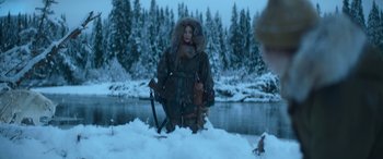 Movie still from “The Mother” (2023), directed by Niki Caro – A woman standing in the middle of a snow covered field; Wide shot, Over the shoulder angle