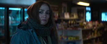 Movie still from “The Mother” (2023), directed by Niki Caro – A person wearing a scarf in a room; Close Up shot, Over the shoulder angle