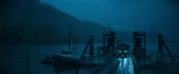 Movie still from “The Mother” (2023), directed by Niki Caro – A boat is docked at a pier in the dark; Extreme Wide shot, High angle