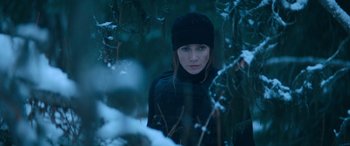 Movie still from “The Mother” (2023), directed by Niki Caro – A woman in a black outfit standing in the snow; Close Up shot, Over the shoulder angle