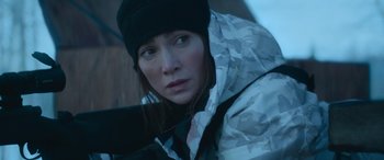 Movie still from “The Mother” (2023), directed by Niki Caro – A person wearing a jacket and a hat; Close Up shot, Over the shoulder angle