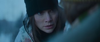 Movie still from “The Mother” (2023), directed by Niki Caro – A person wearing a hat looking at the camera; Close Up shot, Over the shoulder angle