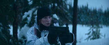 Movie still from “The Mother” (2023), directed by Niki Caro – A woman is holding a gun in the snow; Medium shot, Over the shoulder angle