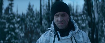 Movie still from “The Mother” (2023), directed by Niki Caro – A person wearing a jacket and a hat; Close Up shot, Over the shoulder angle