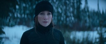 Movie still from “The Mother” (2023), directed by Niki Caro – A person wearing a jacket and a hat; Close Up shot, Over the shoulder angle