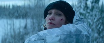 Movie still from “The Mother” (2023), directed by Niki Caro – A person wearing a jacket and a hat; Close Up shot, Overhead angle