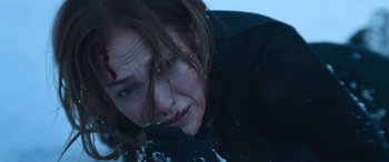 Movie still from “The Mother” (2023), directed by Niki Caro – A person laying in the snow; Close Up shot, High angle