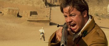 Movie still from “The Mummy” (1999), directed by Stephen Sommers – A man is holding a rifle and aiming at something; Close Up shot, Over the shoulder angle