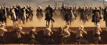 Movie still from “The Mummy” (1999), directed by Stephen Sommers – A group of men on horseback riding across a dirt field; Extreme Wide shot, High angle