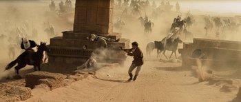 Movie still from “The Mummy” (1999), directed by Stephen Sommers – A man is shooting a gun at another man on a horse; Wide shot, High angle