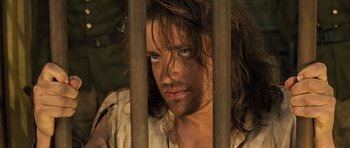 Movie still from “The Mummy” (1999), directed by Stephen Sommers – A person behind a metal fence; Close Up shot, Over the shoulder angle