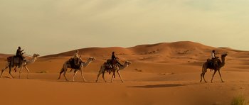 Movie still from “The Mummy” (1999), directed by Stephen Sommers – Two men riding on the backs of camels in the desert; Extreme Wide shot, Low angle