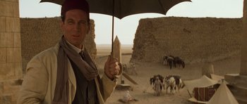Movie still from “The Mummy” (1999), directed by Stephen Sommers – A man holding an open umbrella in a field; Medium shot, Over the shoulder angle
