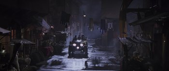 Movie still from “The Mummy” (1999), directed by Stephen Sommers – An old car driving down a street at night; Extreme Wide shot, High angle