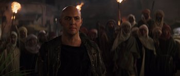 Movie still from “The Mummy” (1999), directed by Stephen Sommers – A man with a bald head standing in front of a group of people; Close Up shot, Over the shoulder angle