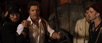Movie still from “The Mummy” (1999), directed by Stephen Sommers – A man holding a wooden stick while standing next to a wagon; Close Up shot, Over the shoulder angle