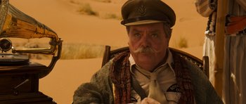 Movie still from “The Mummy” (1999), directed by Stephen Sommers – An older man with a mustache wearing a hat and a tie; Close Up shot, Over the shoulder angle